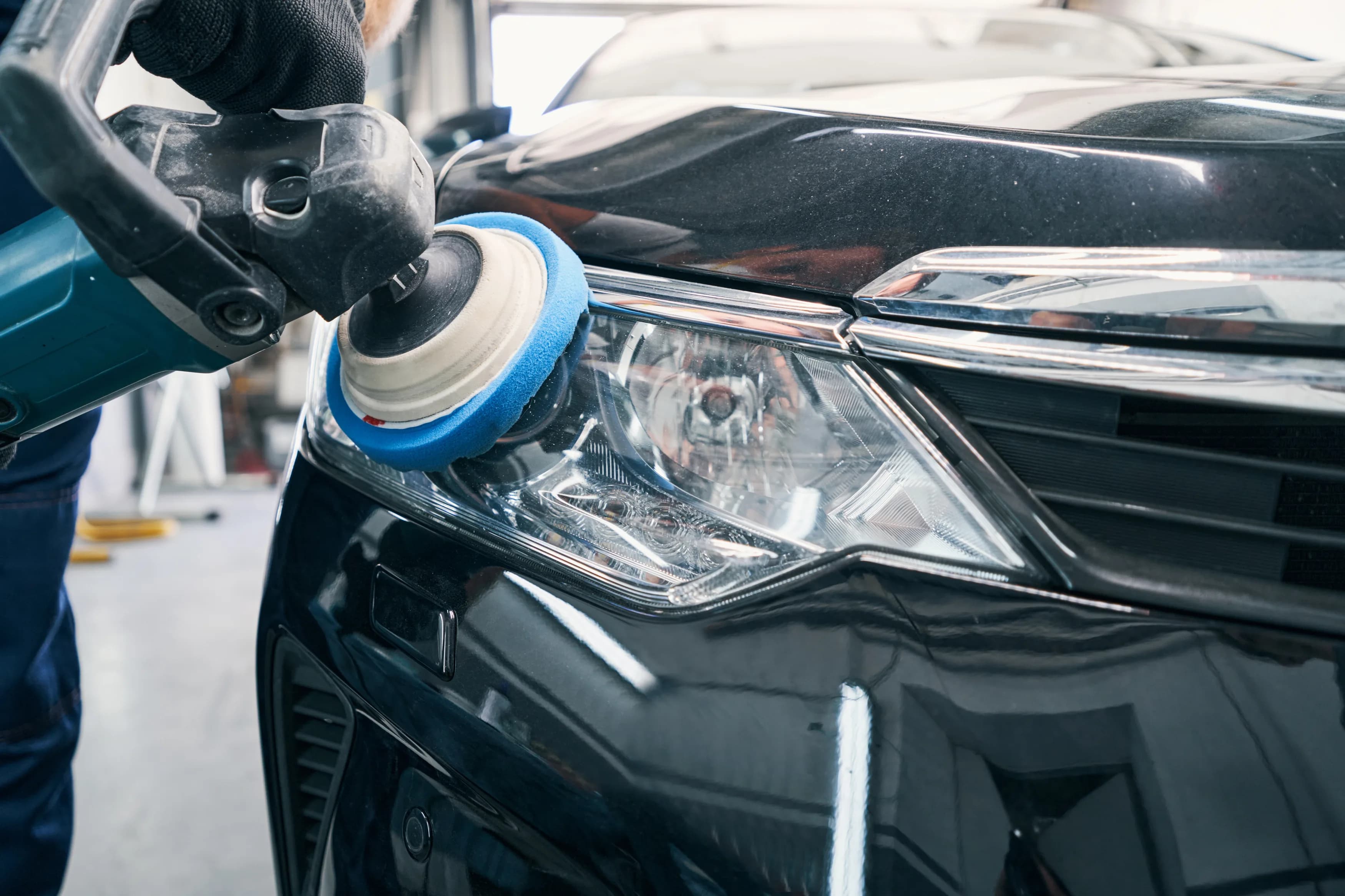 A detailer machine-polishing a headlight lens back to clear