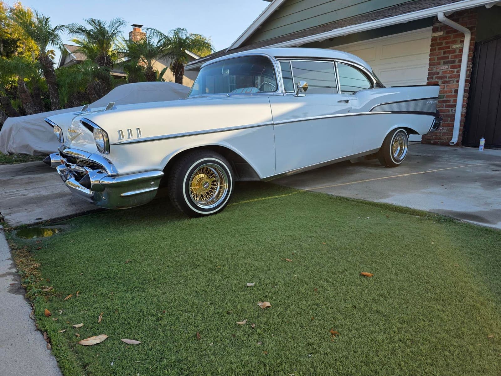 White 1957 Chevy Bel Air side profile with gold wire wheels and whitewalls, freshly detailed