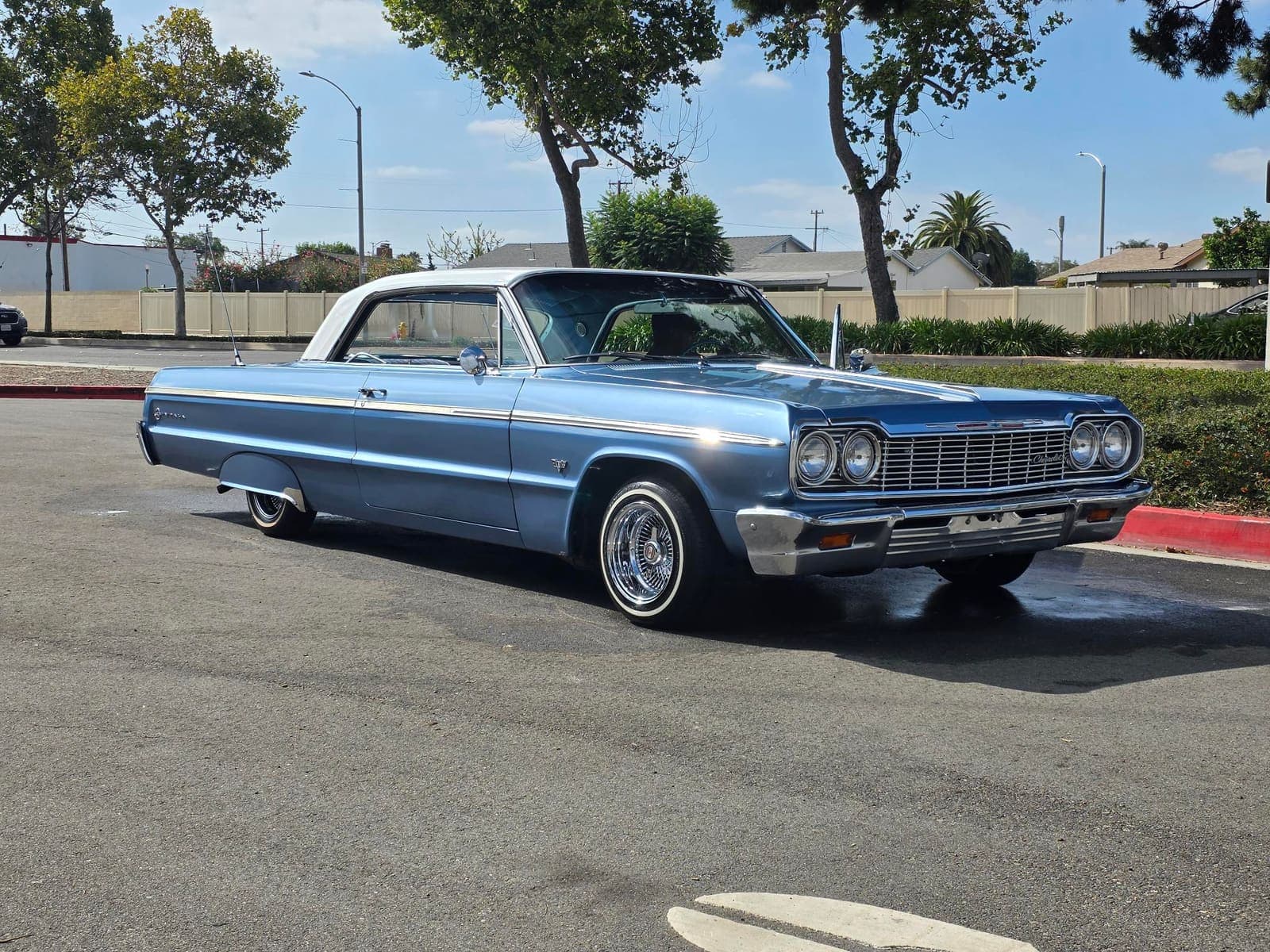 Light blue 1964 Chevy Impala with white top, front three-quarter view after a full detail