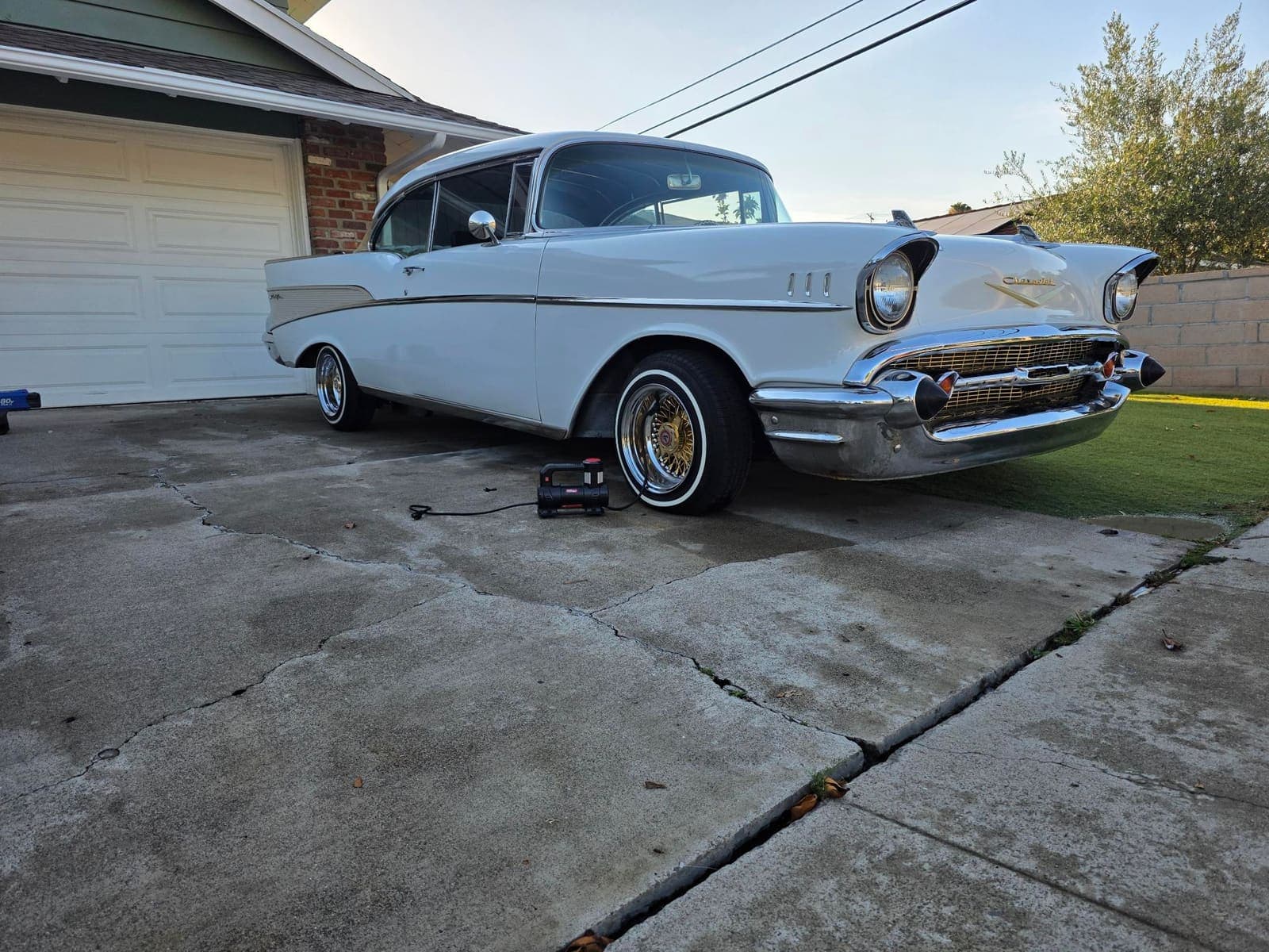1957 Chevy Bel Air front three-quarter with chrome bumper shining in the driveway