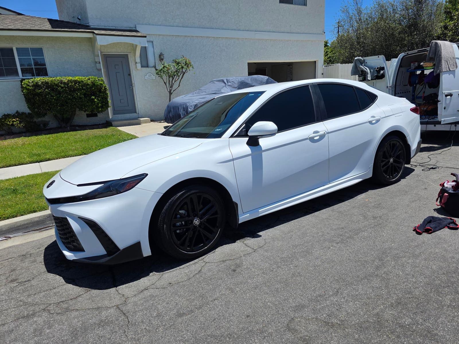 White Toyota Camry with black wheels and tinted windows, freshly detailed side profile