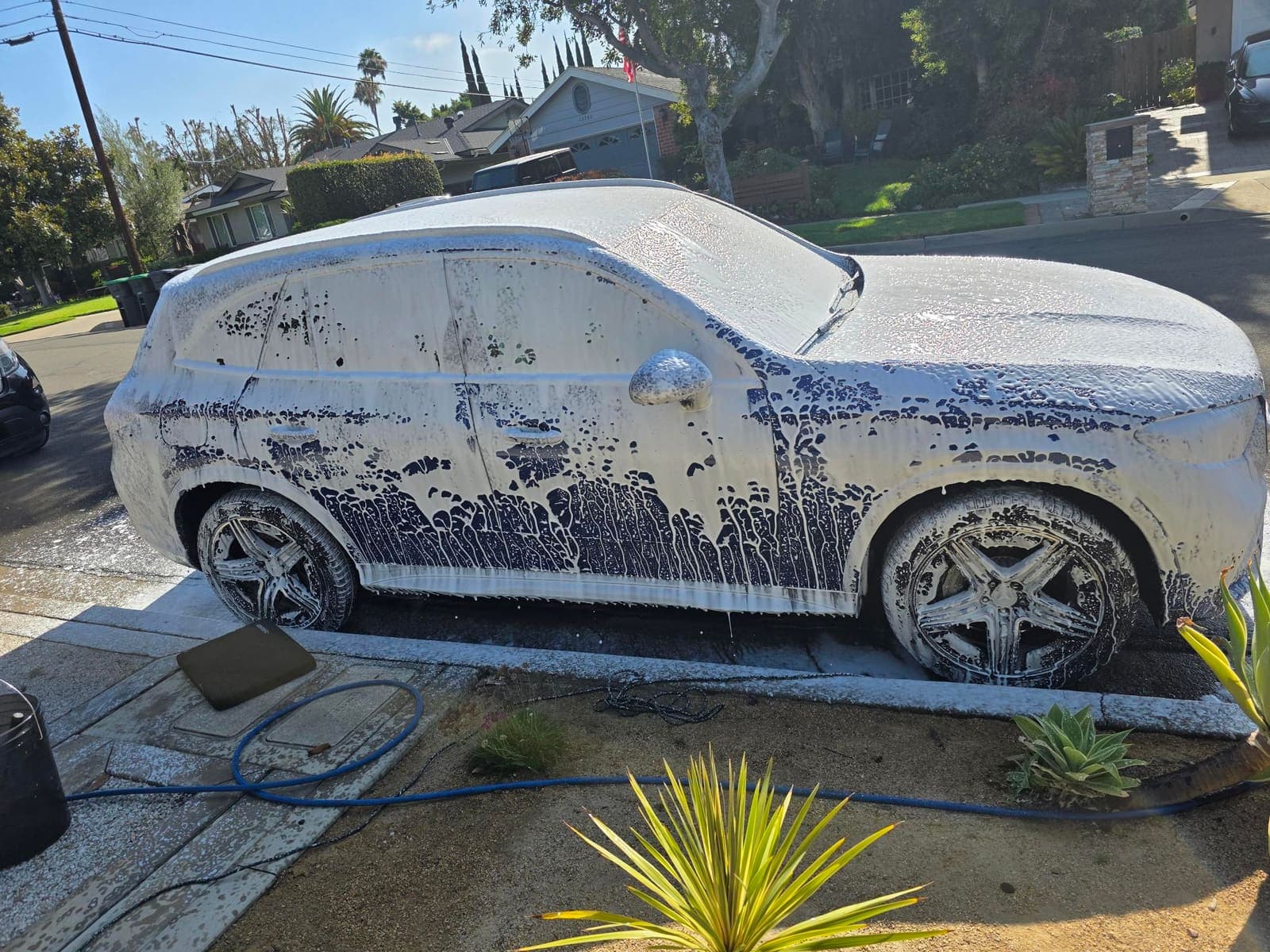 Blue Mercedes GLC covered in thick snow foam during a hand wash