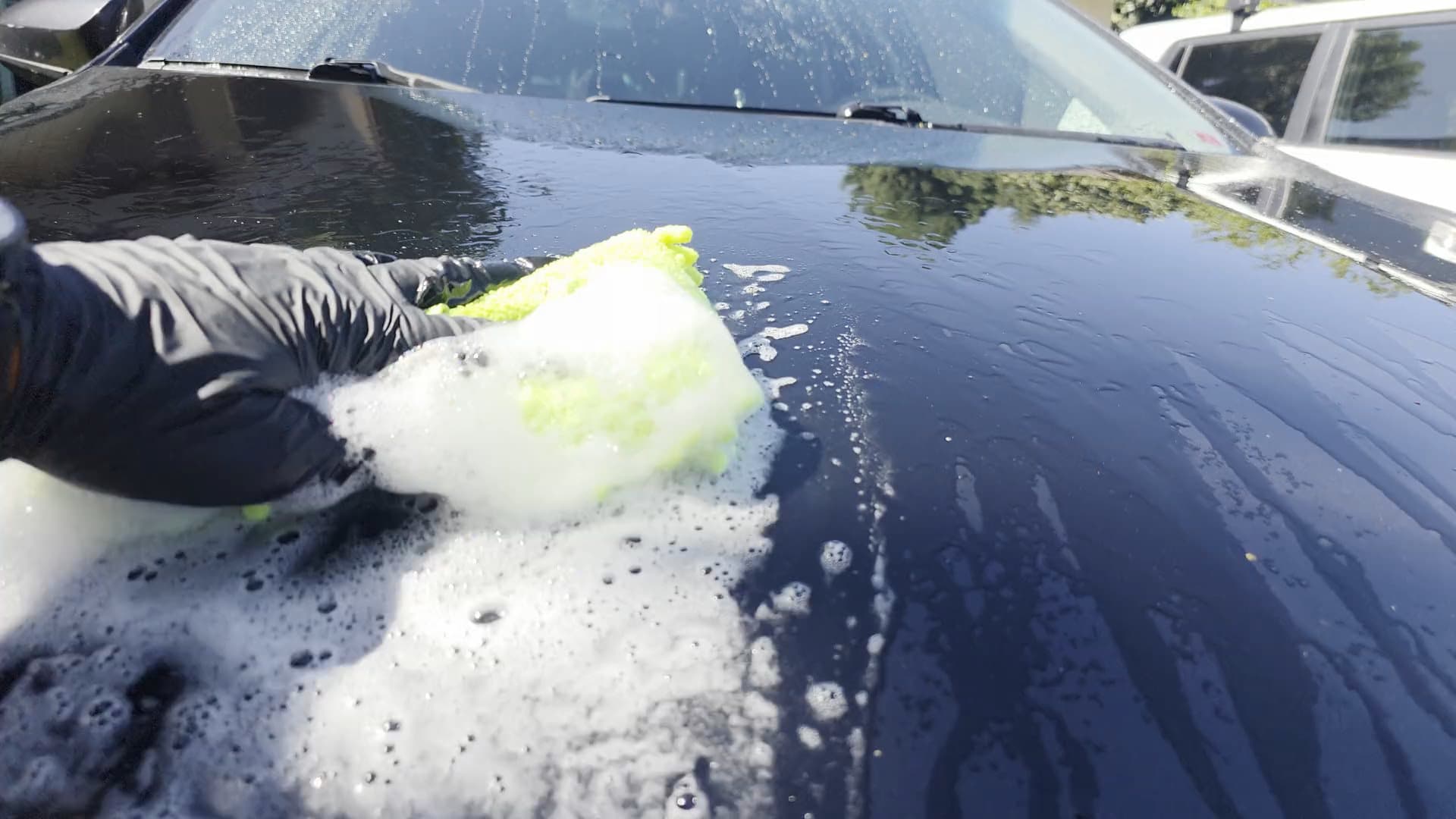 NV Auto Detail sudsing and rinsing a car in an Orange County driveway