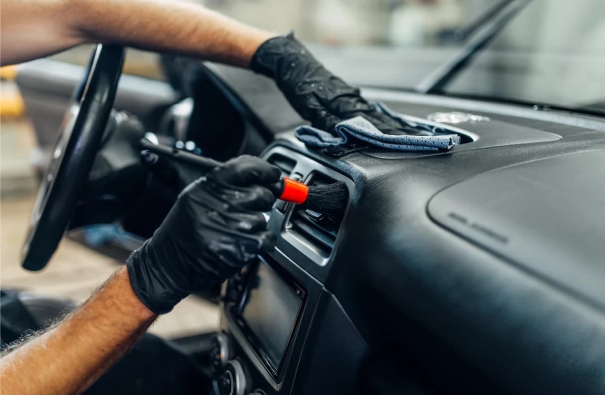 Close-up of a microfiber wipe cleaning a leather car interior